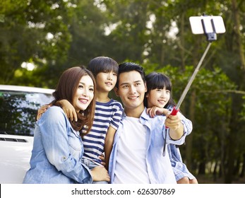 Asian Family With Two Children Taking A Selfie During A Trip.