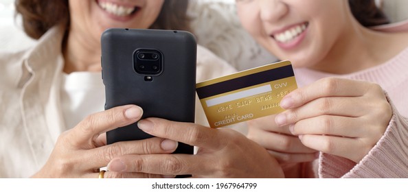 Asian Family Two People Satisfaction Pay Transfer Money Online Tech In Living Room Sofa Couch In Social Commerce Shop Promotion, Urban Life Omni Channel Fintech Connect In Diverse Generation Concept.