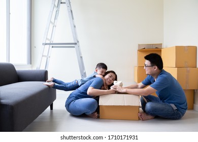 Asian Family Unpacking Cardboard Boxes At New Home, Relocating For New Real Estate Property Concept