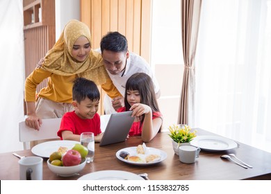 Asian Family Using Tablet Pc At Home During Breakfast In The Morning