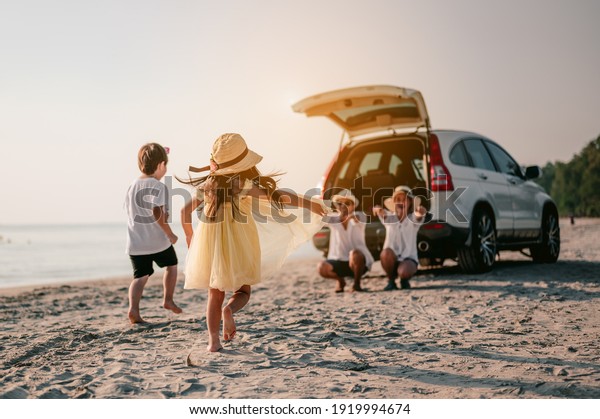 Asian family\
vacation holiday, Happy family running on the beach in the\
sunset.\
Children are running to their parents behind cars.Holiday\
and travel family concept, Summer\
vacations.