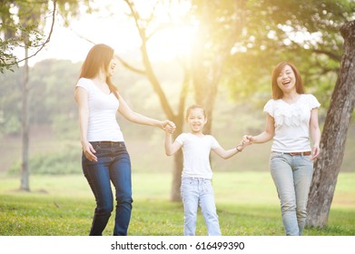 Asian Family Walking At Nature Park, Outdoor In Morning With Sun Flare.