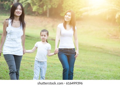 Asian Family Walking At Nature Park, Morning Outdoor With Sun Flare.