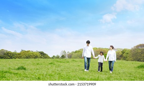Asian family walking on the green field. Environment concept. Childcare. Sustainable lifestyle.