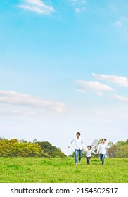 Asian Family Walking On The Green Field. Environment Concept. Childcare. Sustainable Lifestyle.