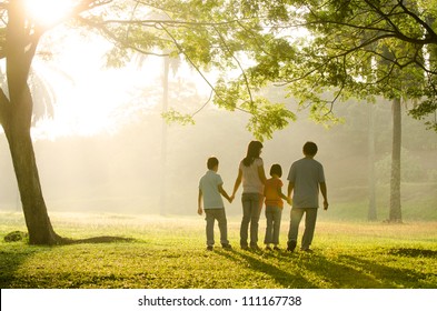 an asian family walking in the park during a beautiful sunrise, backlight - Powered by Shutterstock