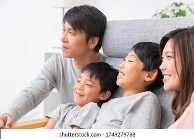 Asian Family Watching TV In Living Room