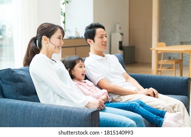 Asian Family Watching TV In Living Room.