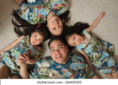 Asian Family Wearing Hawaiian Shirts Laying On Floor Smiling
