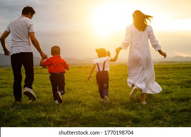  Asian Family.Family Running In The Meadow Behind The Sunset.