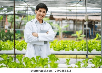 Asian farm researcher standing with his arms crossed takes care of vegetables growing on farm. farming is sustainable agriculture for future food. - Powered by Shutterstock