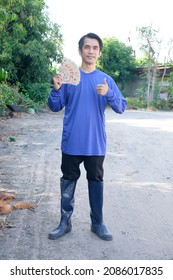 Asian Farmer Man Smile Holding Thailand Banknote Money Standing At Farm. Full Body Image.