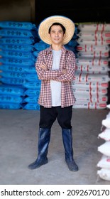 Asian Farmer Man Standing And Cross Arms At Chemical Fertilizer Store Warehouse. Full Body Portrait Image