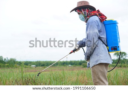 Asian farmer uses herbicides, insecticides chemical spray to get rid of weeds and insects or plant disease in agricultural land. Cause air pollution. Environmental , Agriculture chemicals concept. 