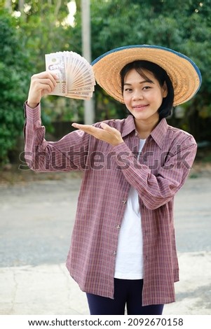 Asian farmer woman holding Thailand banknote money and pose for promotion sale.