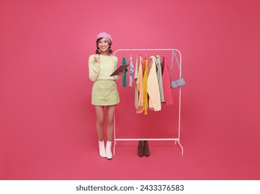 asian fashion manager with a checklist in retail store clothes or clothing inspection isolated on pink background. Entrepreneur, shopping and small business owner writing stock  - Powered by Shutterstock