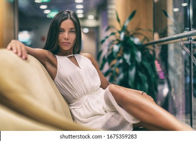 Asian Fashion Model Posing In White Dress On Luxurious Sofa In Cruise Ship. Beauty Young Woman High End Resort.