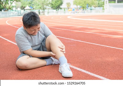 Asian Fat Boy Holding His Sports Leg Injury. Muscle Painful During Training. Kid Runner Having Calf Ache And Problem After Running On Track. Sport And Healthy Concepts