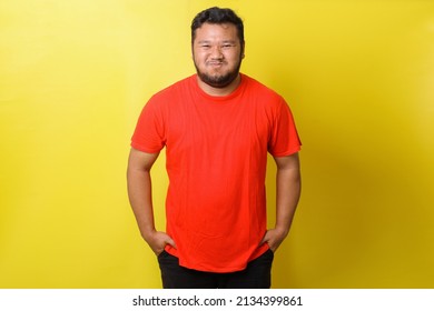 Asian fat man in red tshirt is simpering smile  isolated on yellow background  - Shutterstock ID 2134399861