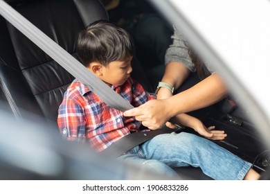 Asian Fat Woman Fastening Child With Safety Seat Belt In Car.