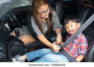 Asian Fat Woman Fastening Child With Safety Seat Belt In Car.