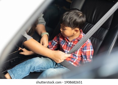 Asian Fat Woman Fastening Child With Safety Seat Belt In Car.