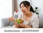 An Asian fat woman feels bad and bored while eating a salad. She doesn