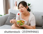 An Asian fat woman feels bad and bored while eating a salad. She doesn