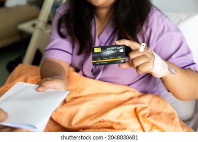 Asian Fat Woman Patients Lying In Hospital Patient Bed And Show Creditcard Mock Up In Hand.