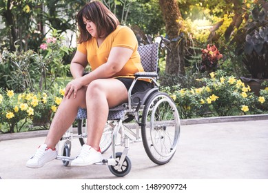Asian fat woman are Patients sitting on a wheelchair She can't walk Have a knee pain Due to excessive weight and many complications From cholesterol, to health care concept.