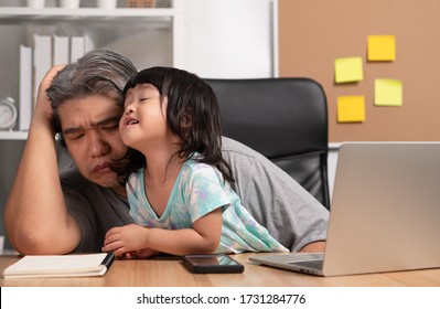 Asian Father Attempt To Work At The Home Office With A Laptop With A Daughter Who Came Into Chaos. New Lifestyle Normal During A Quarantine. Concept Of Stay Home, Freelance And Fatherhood Concept