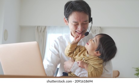 Asian Father And Baby Working At Home