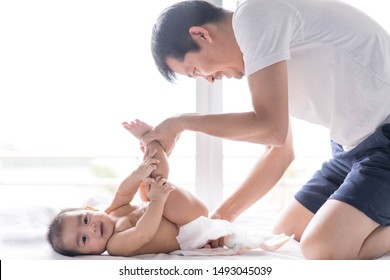 Asian Father Is Changing Diapper For His Little Baby Boy In The Morning Time And The Boy Express Happy Moment With His Smiley Face, Concept Of Role Of Father To Care Their Child In Family Life.