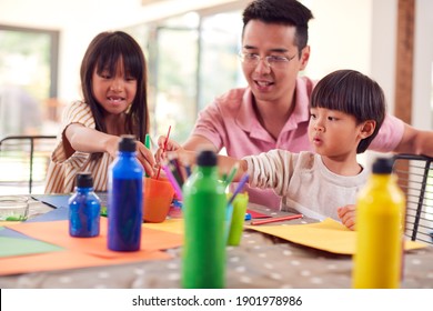 Asian Father With Children Having Fun With Children Doing Craft On Table At Home