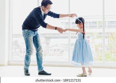An Asian father and daughter are dancing, dad teaches daughters to dance in a fun room.