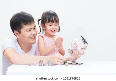 Asian Father And Daughter Are Insert The Coins To Piggy Bank Together With Fully Happiness Moment, Concept Of Financial Education And Learning Activity For Kid In Family Lifestyle.