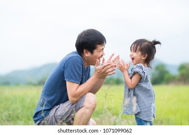 Asian Father And Daughter Are Playing And Laughing Together With Fully Happiness Moment In The Background Of Sky And Mountains.