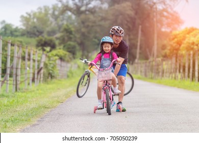 Asian Father And Daughter Riding Bicycles On The Street