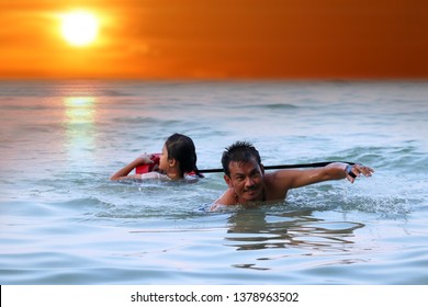 Asian father and daughter are teaching and training life guard or rescue on the beach in the evening. - Powered by Shutterstock