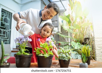 Asian father and daughter using watering can to watering potted plants to fill activities at home - Powered by Shutterstock