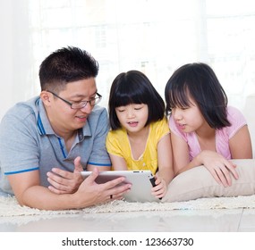 Asian father and daughters using tablet computer at home - Powered by Shutterstock