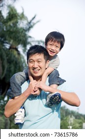 Asian Father Giving Piggyback Ride To His Son In The Evening Sunshine