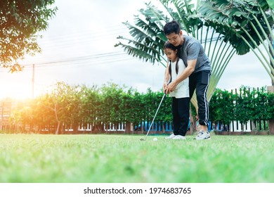 Asian Father And Giving Young Daughter Golf Lesson.