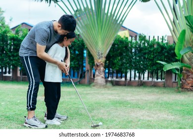 Asian Father And Giving Young Daughter Golf Lesson.