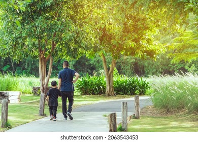 Asian father hand holding lovely son walking on pathway through green garden. Dad and son walking together in park. Happy family spending time together outside in green nature. Enjoying nature outdoors. - Powered by Shutterstock