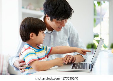 Asian Father Helping Son To Use Laptop At Home