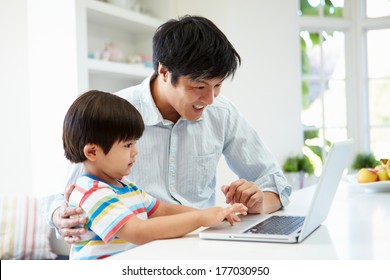 Asian Father Helping Son To Use Laptop At Home