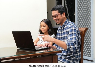 Asian Father And His Daughter Looking To The Laptop Screen With Happy Face