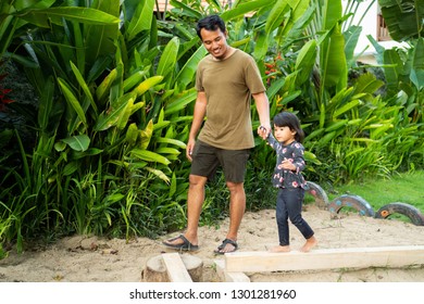 Asian Father Holding A Daughter Hands When Playing Balance Beam In The Park