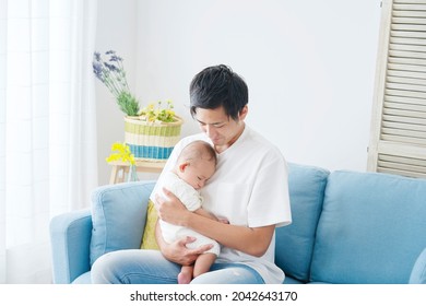 Asian Father Holding His Baby On The Sofa